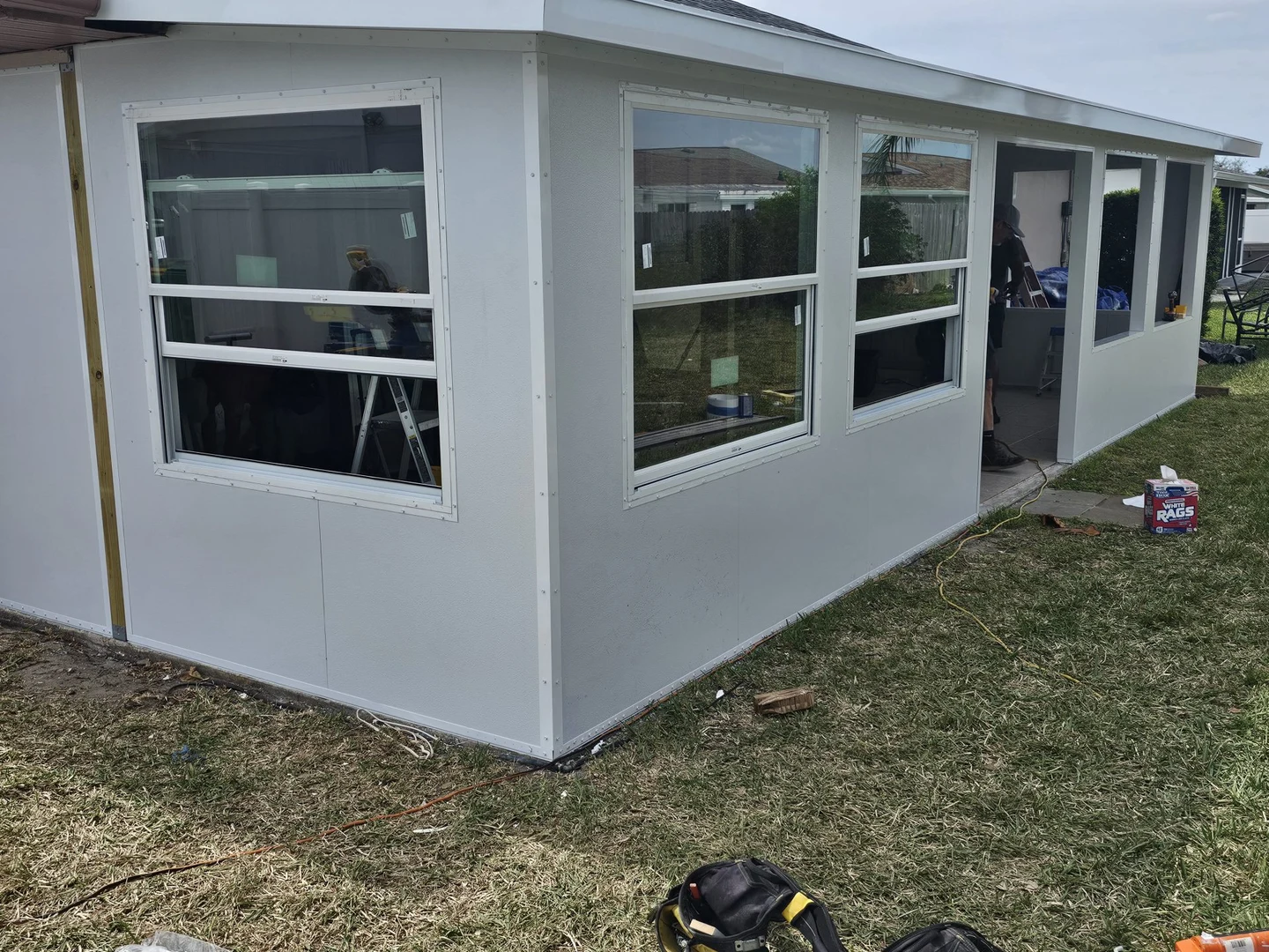 Room enclosure with white-framed windows, tools and an unfinished doorway visible.