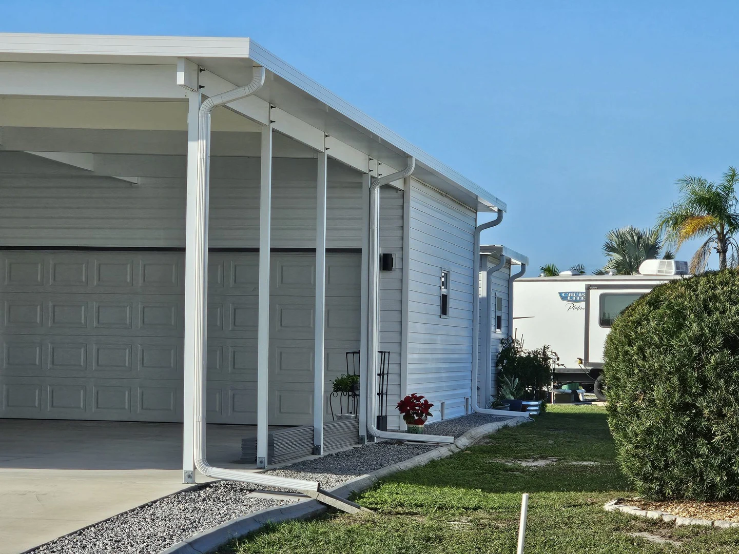 Covered garage-side area with white posts and visible downspouts.
