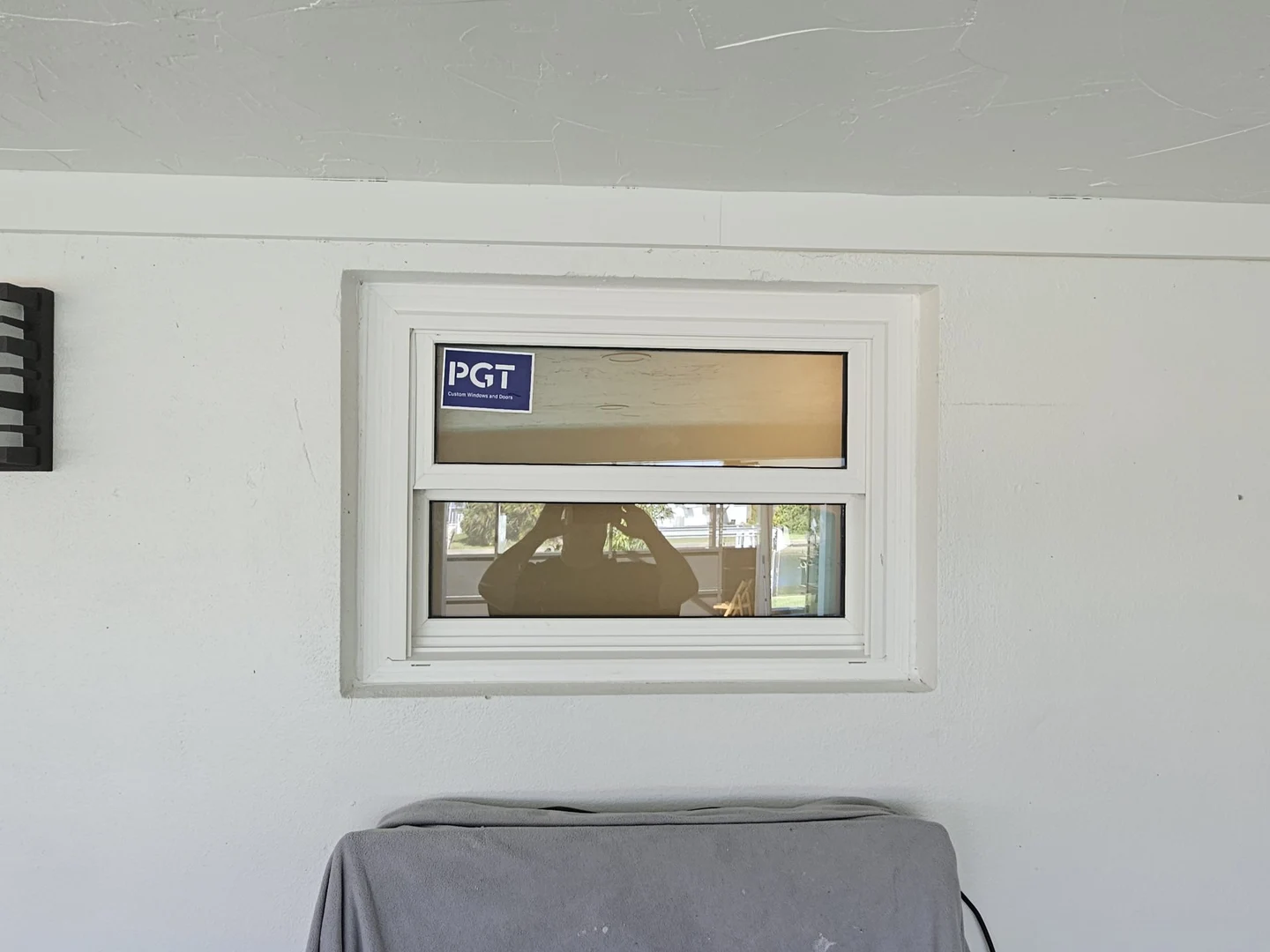 Stickered white-framed window above covered furniture during installation.