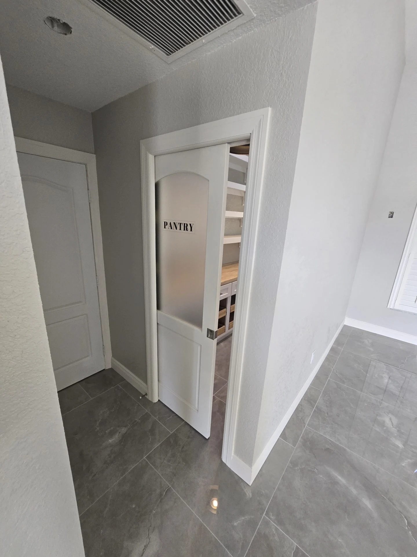White casing around a partially open pantry door, with baseboard meeting the doorway.