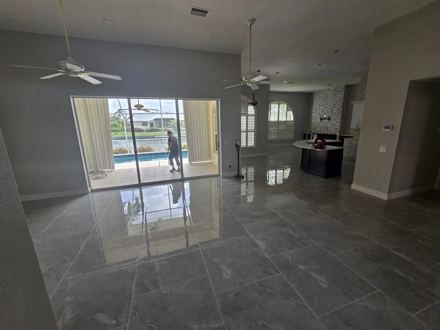 Light-filled living area with polished gray tile flooring and sliding glass doors.